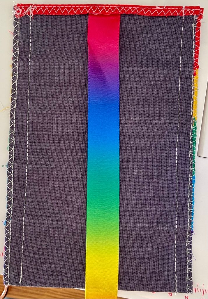 The piece of fabric folded in half and sewn together on both sides. The rainbow coloured ribbon is sewn into the upper seam